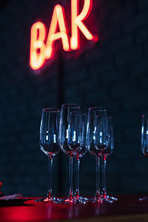 Glasses on bar neon sign backgroundの写真素材
