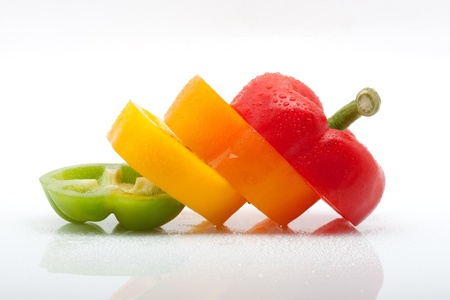 fresh slices of red, green, yellow and orange pepper with water drops isolated on white background