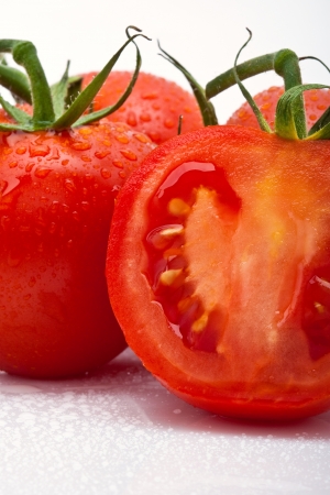 closeup of juicy tomato slice ?with drops against white backgroundの写真素材