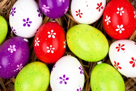 closeup of colorful painted easter eggs hidden in a nest of straw