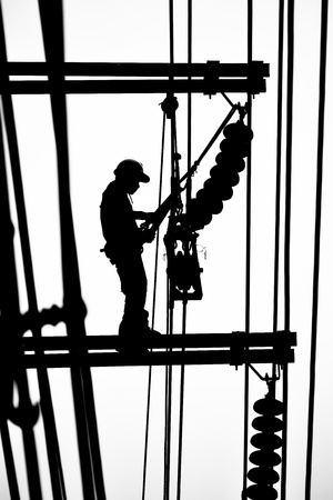 silhouette electrician working on electricity postの写真素材