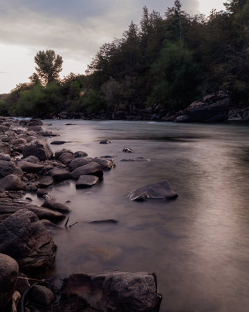 dusk on a river bank with many stones on a cloudy day