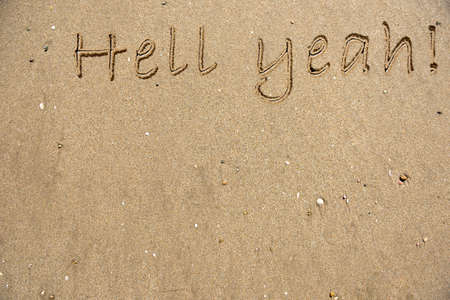The words Hell Yeah written on sandの写真素材