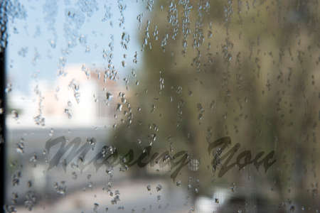 Missing you written on glass pane