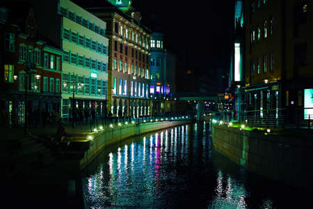 Aarhus River running through the city centre taken at night with the light from the buildings being...