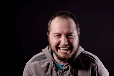 happy young man smiling at the camera isolated on black backgroundの写真素材