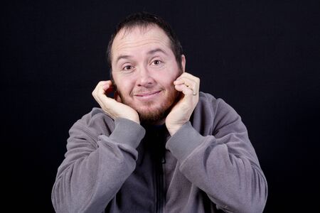 Portrait of man with hands under the chin looking into the camera, isolated on black