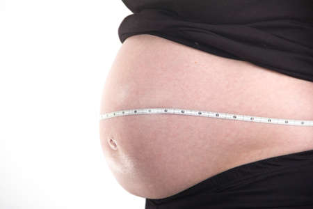 pregnant woman close up belly measure isolated on white backgroundの写真素材