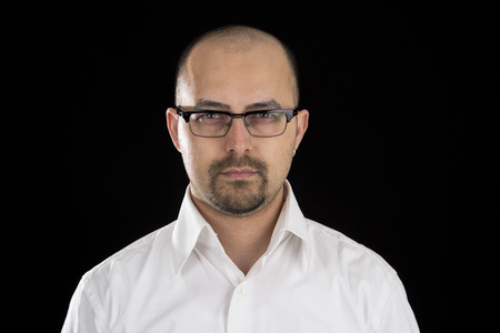 portrait of handsome young man wearing glasses against black background