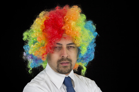 business man wearing colorful wig looking boredの写真素材