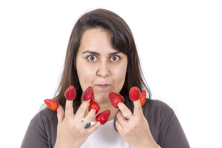 fat woman holding strawberryies on fingers and look funny