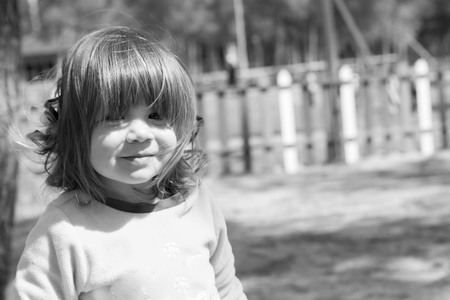 baby girl looking in camera smiling outdoor black and white photoの写真素材