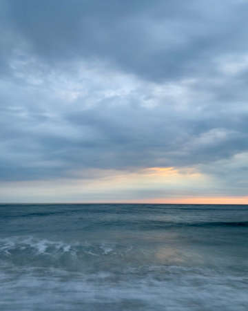 Photograph of sunrise over water taken from the beach shoreの写真素材