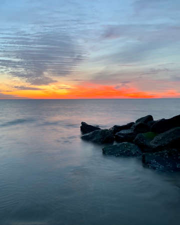 Photograph of sunrise over water taken from the beach shoreの写真素材