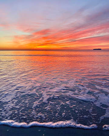 Photograph of sunrise over water taken from the beach shoreの写真素材