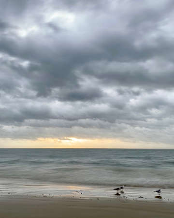 Sunrise over dark ocean waterの写真素材