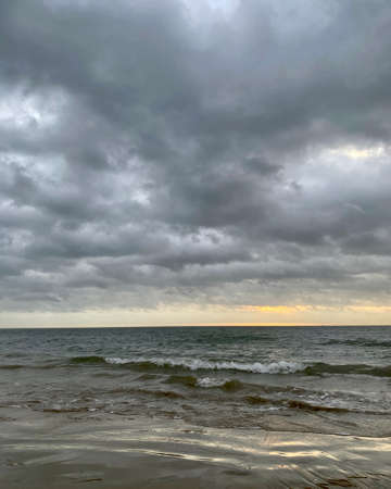 Sunrise over dark ocean waterの写真素材