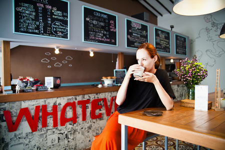 Beautiful young woman enjoying coffee latte in cafe beside the bar, beauty model woman with the cup of hot beverage.のeditorial素材
