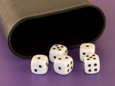 Closeup of five white dices and a cup lying on a tableの写真素材