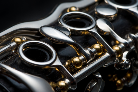 Details of a clarinet with silver keys and golden sockets on black backgroundの写真素材