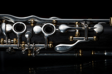 Details of a clarinet with silver keys and golden sockets on black backgroundの写真素材