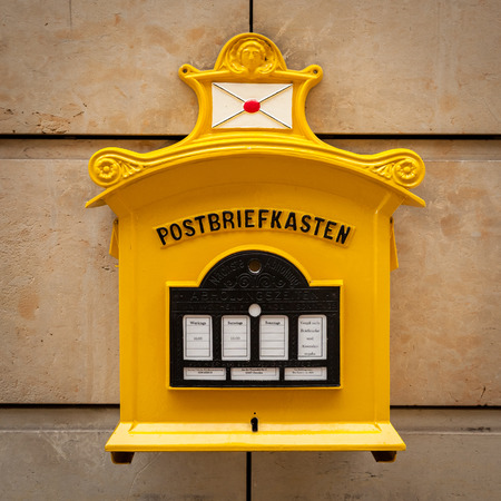 An old vintage yellow mailbox in Dresden Germany with inscriptionのeditorial素材