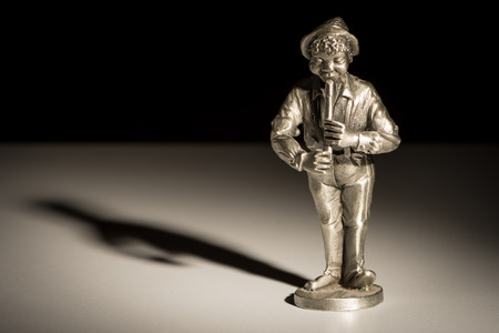 Closeup of a small figurine of a flute player black backgroundの写真素材