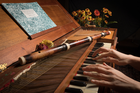 Closeup of an old baroque clavichord and wooden traverse flute hands playingの写真素材