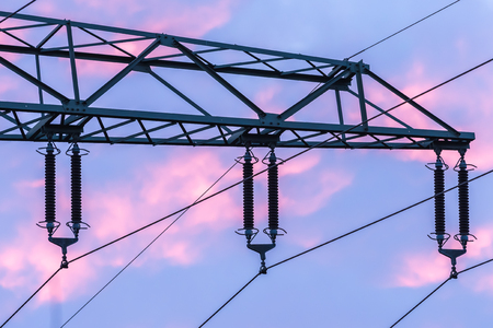 Detail of a high voltage power cable during sunset pink clouds