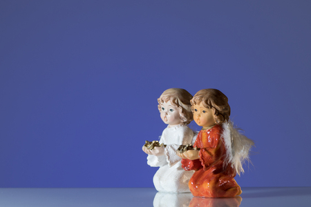 Closeup of two angels made of porcelain, blue backgroundの写真素材