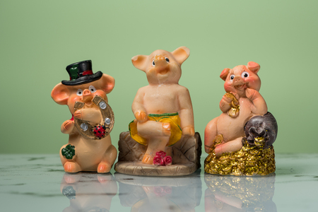 Closeup of three figurines of New Year's piggies, green backgroundの写真素材