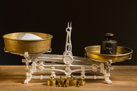Old white vintage kitchen scale, brass with weights and sugar on a kitchen tableの写真素材