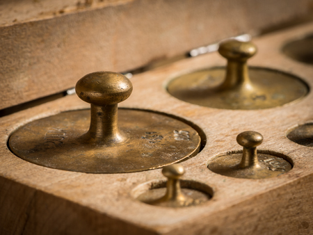 Old brass weights for a kitchen scale in a wooden boxの写真素材