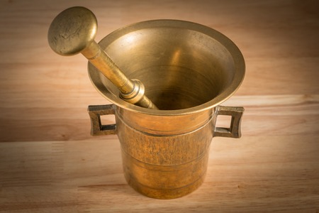 Mortar made of brass standing on a brown wooden tableの写真素材