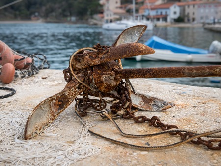 Small rusty anchor with chain lying on the ground, Croatiaの写真素材