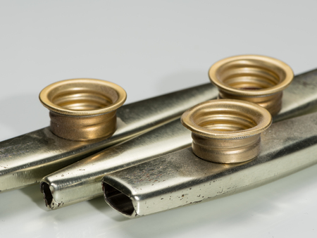 Closeup of metal kazoos on a white reflective surfaceの写真素材
