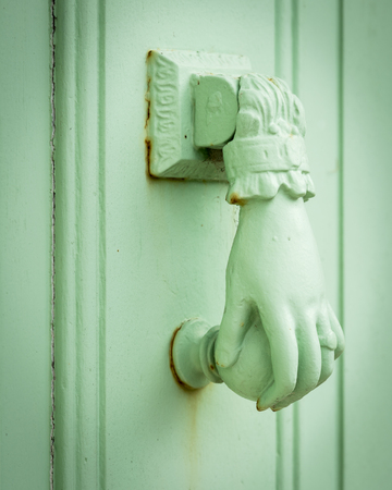 Closeup of a pastel green colored doorknocker in the form of a handの写真素材