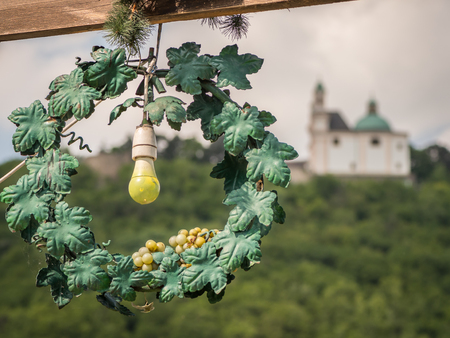 Yellow light bulb in a green wreath sign for a tavern in front of Leopoldsberg (Vienna, Austria)の写真素材
