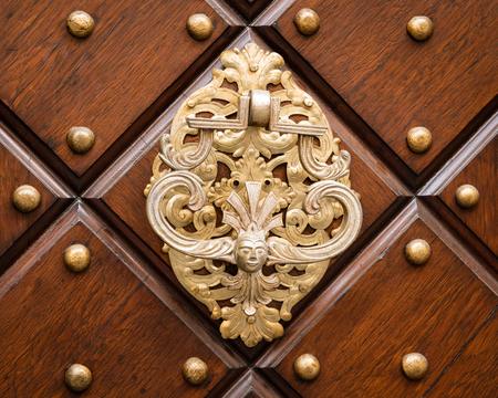 Closeup of a beautiful old doorknob made of silver on a brown door