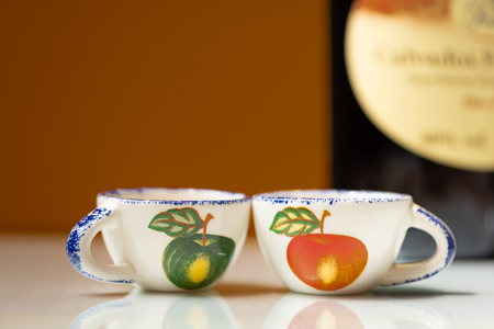Closeup of two small cups with painted apples for drinking apple brandyの写真素材