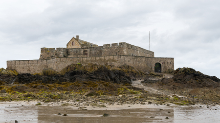 The beach and Fort National during low tide in Saint Malo (Bretagne, France) on a cloudy day in summerの写真素材