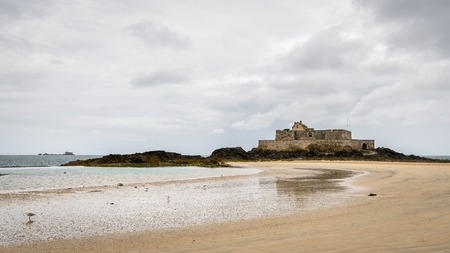 The beach and Fort National during low tide in Saint Malo (Bretagne, France) on a cloudy day in summerの写真素材