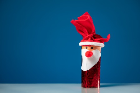 A figure of Santa made of a toilet paper roll by a child on blue backgroundの写真素材