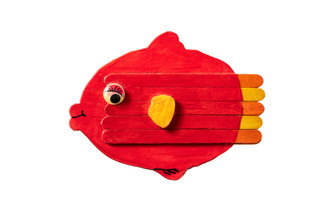 Figure of a colorful red fish made of wood by a child on white backgroundの写真素材
