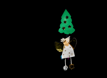 A handicraft of an angel and a christmas  made by a child out of paper on black backgroundの写真素材