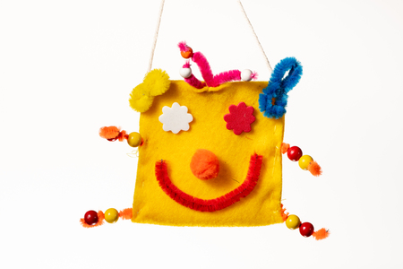 A colorful bag with the face of a clown made by a child on whiteの写真素材