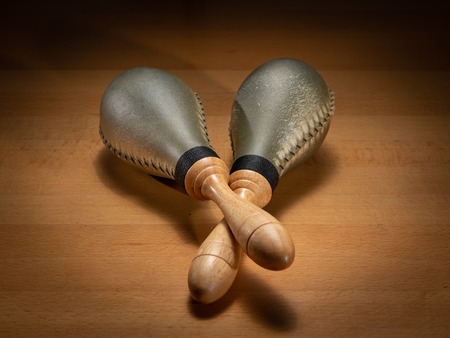 Closeup of a pair of rawhide maracas lying on a wooden tableの写真素材