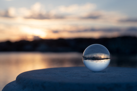 Sunset through glass ball in the harbor of Cres (Croatia) on a partly cloudy day in springの写真素材