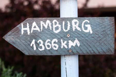grey sign with white font on a white pole which points to Hamburgの写真素材
