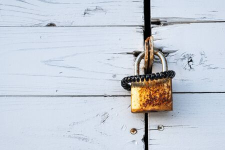 rusty lock with black scrunchy hanging on a wooden door in the evening sunの写真素材